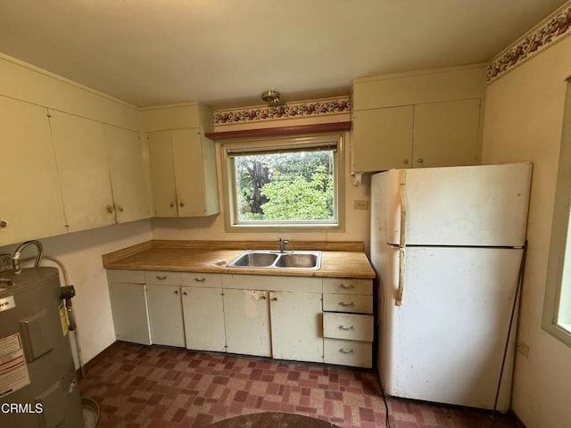 kitchen featuring a sink, light countertops, freestanding refrigerator, and water heater
