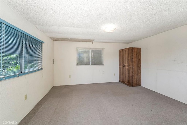 carpeted empty room with a textured ceiling
