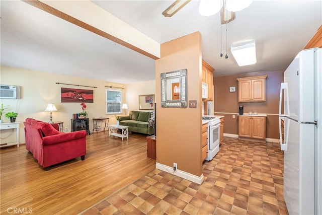 kitchen featuring white appliances, light countertops, open floor plan, light brown cabinets, and baseboards