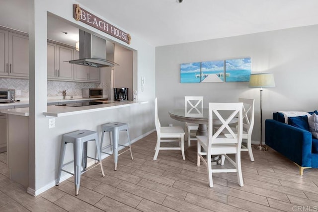 4007 Everts St Unit 4H, Pacific Beach San Diego, CA 92109 - kitchen featuring gray cabinets, a kitchen breakfast bar, wall chimney exhaust hood, stainless steel microwave, and light wood-style flooring