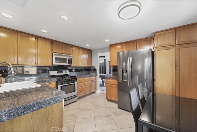 39878 Teal Dr, Murrieta, CA 92562 - kitchen featuring dark countertops, light tile patterned floors, a sink, tasteful backsplash, and appliances with stainless steel finishes