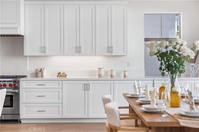 kitchen with light countertops, high end range, and white cabinetry
