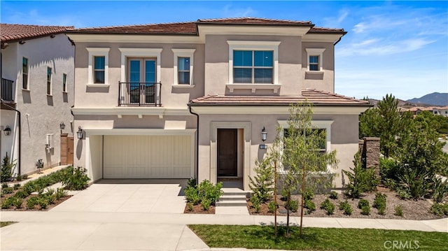 view of front of home featuring stucco siding, concrete driveway, a balcony, and a garage