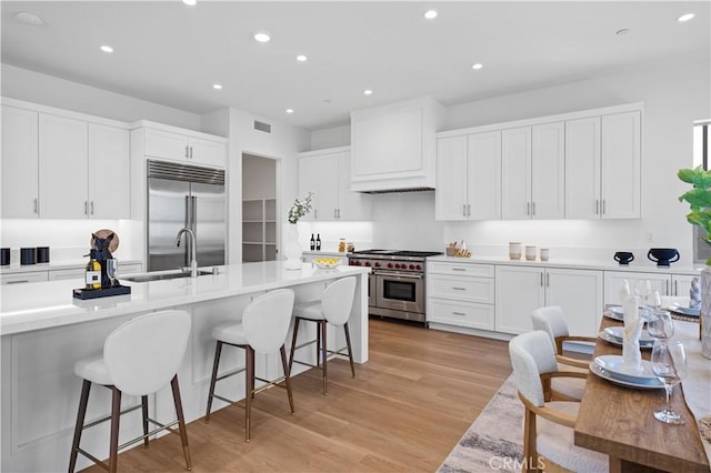 kitchen with white cabinets, high quality appliances, a sink, and a breakfast bar