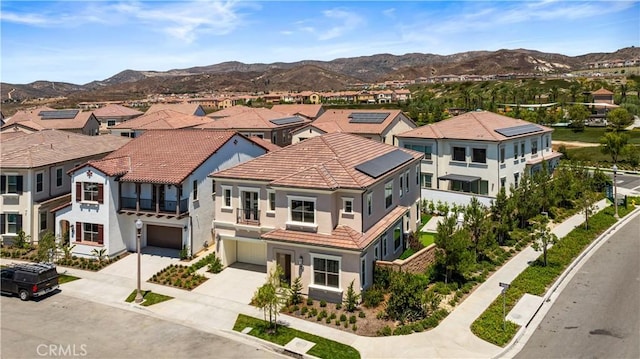 view of front of property featuring a residential view, an attached garage, a tile roof, and concrete driveway