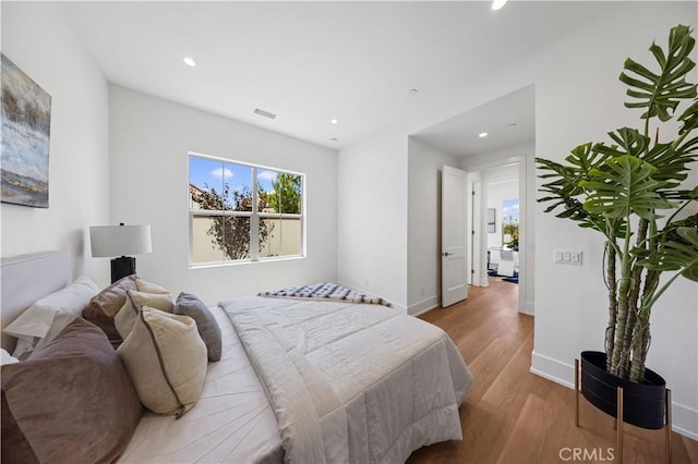 bedroom featuring baseboards, wood finished floors, visible vents, and recessed lighting