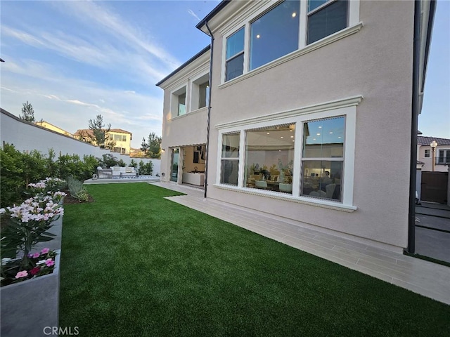 rear view of house featuring outdoor lounge area, a patio area, a lawn, and stucco siding