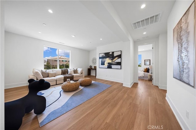 living area featuring baseboards, light wood-style floors, visible vents, and recessed lighting