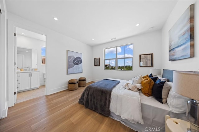 bedroom with ensuite bath, recessed lighting, a sink, and light wood-type flooring