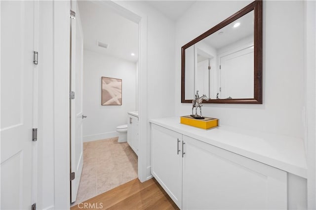 bathroom with baseboards, toilet, vanity, and recessed lighting