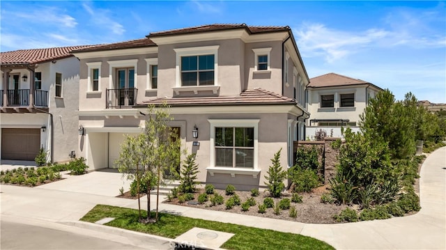view of front of house with stucco siding, an attached garage, a tile roof, and driveway