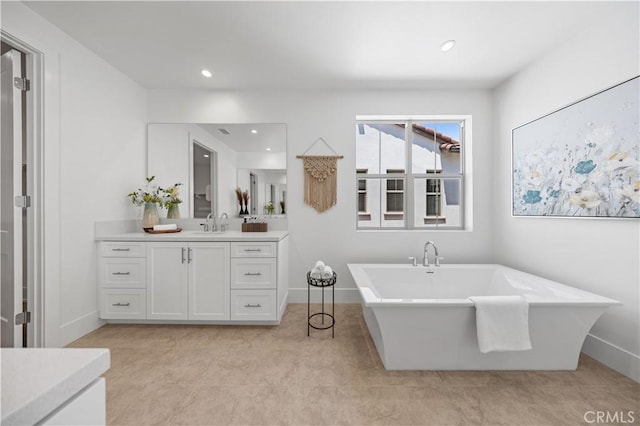 bathroom with recessed lighting, tile patterned floors, vanity, baseboards, and a soaking tub