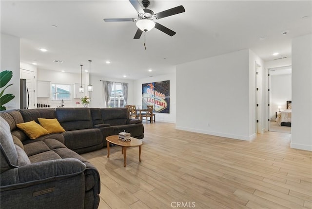 living room featuring light wood-type flooring, baseboards, a ceiling fan, and recessed lighting
