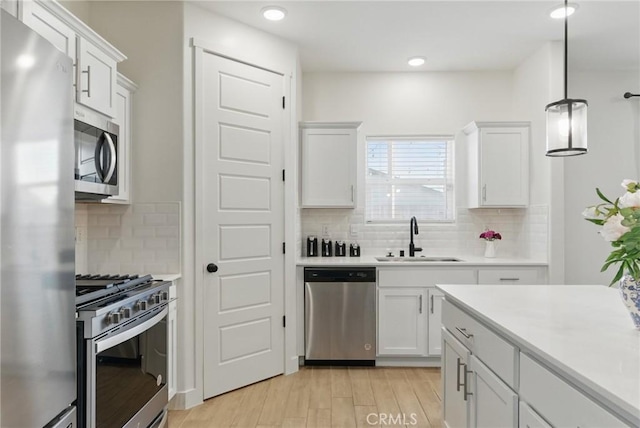 kitchen with light countertops, tasteful backsplash, a sink, and stainless steel appliances