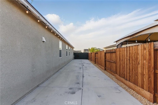 view of side of property with a patio area, stucco siding, and fence