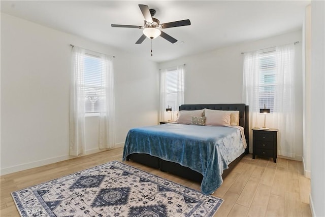bedroom with light wood finished floors, baseboards, and a ceiling fan