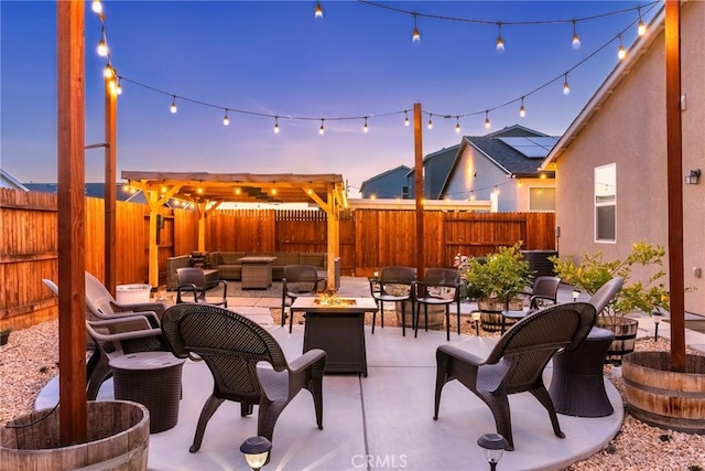 patio terrace at dusk featuring a fenced backyard and a fire pit