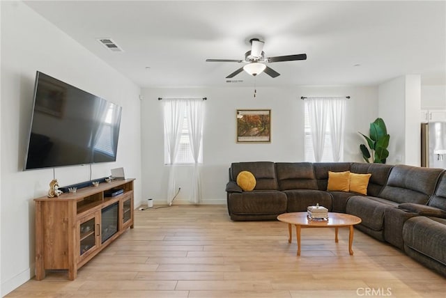 living area featuring a healthy amount of sunlight, light wood-style floors, visible vents, and ceiling fan
