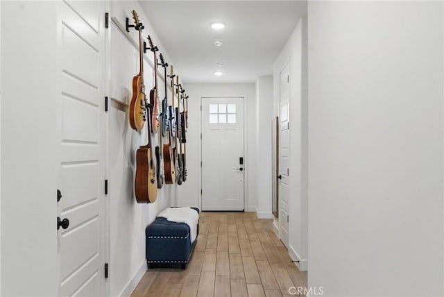 mudroom with a barn door, recessed lighting, light wood-type flooring, and baseboards