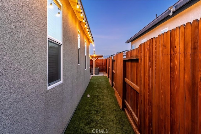 view of home's exterior with stucco siding, a fenced backyard, and a lawn