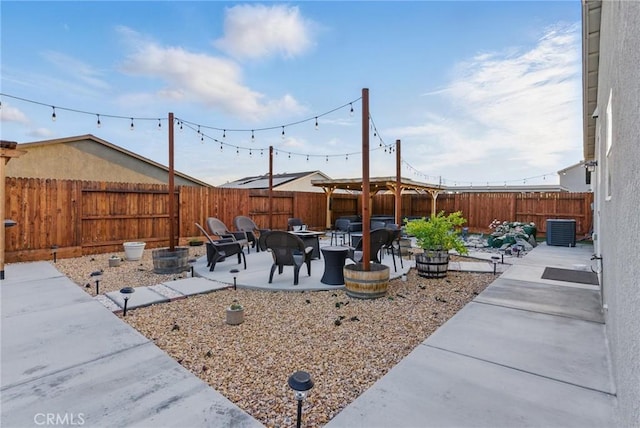 view of yard featuring a patio area, central AC unit, a fenced backyard, and an outdoor fire pit