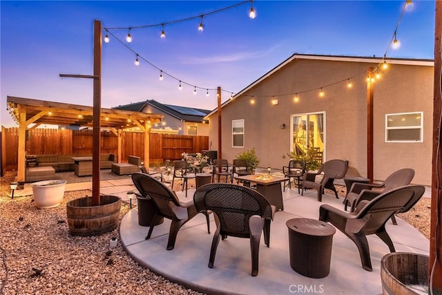 patio terrace at dusk featuring an outdoor living space with a fire pit and fence private yard