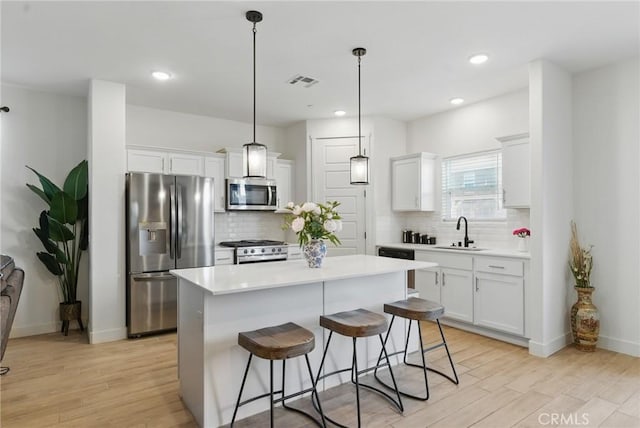 kitchen featuring a sink, light wood-type flooring, appliances with stainless steel finishes, and decorative backsplash