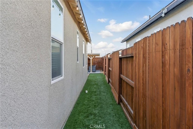 view of property exterior with stucco siding, a fenced backyard, and a lawn