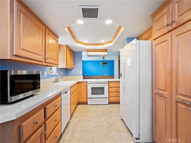 kitchen with a sink, white appliances, light countertops, visible vents, and a raised ceiling