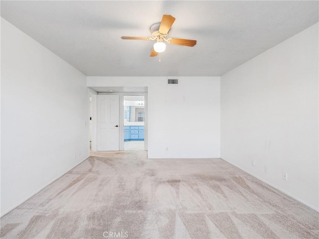 empty room featuring carpet floors, visible vents, and ceiling fan