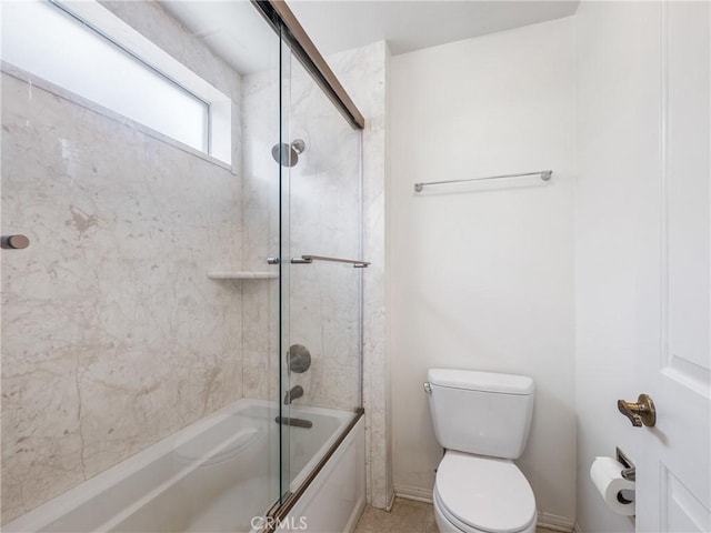 bathroom featuring toilet and bath / shower combo with glass door