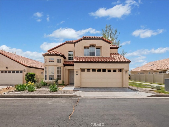 mediterranean / spanish home with a tile roof, stucco siding, and fence