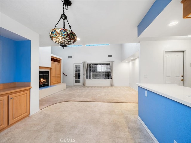 unfurnished living room with a warm lit fireplace and light carpet