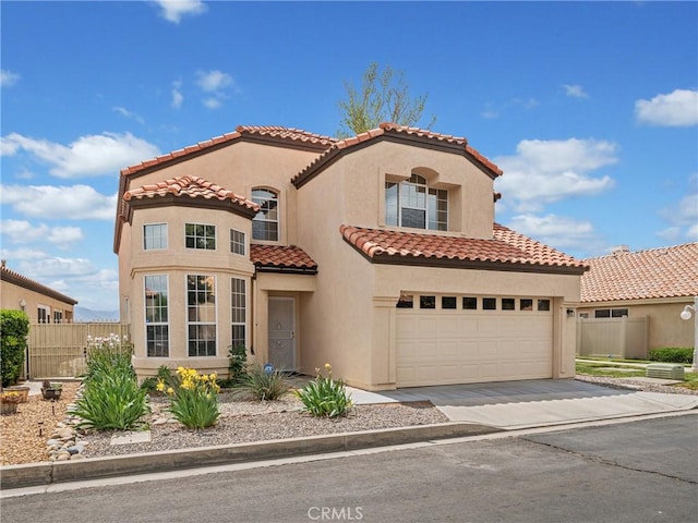 mediterranean / spanish home featuring driveway, a tile roof, stucco siding, and fence
