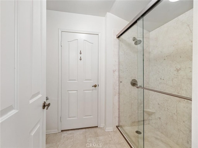 bathroom with a shower stall and baseboards