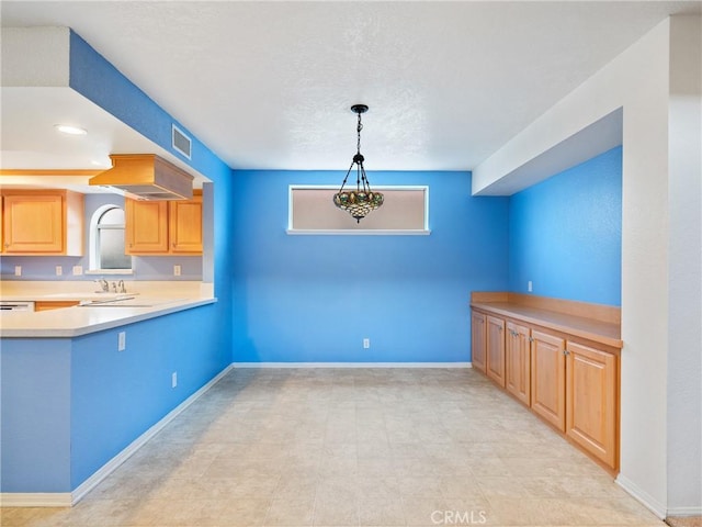 kitchen with light countertops, decorative light fixtures, a wealth of natural light, and visible vents