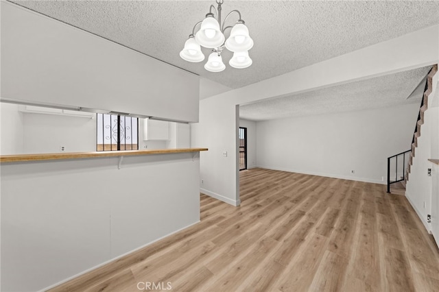1144 N Lyman Ave, Covina, CA 91724 - unfurnished living room with a wealth of natural light, stairs, a notable chandelier, and a textured ceiling