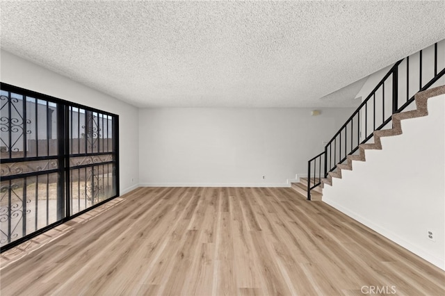 1144 N Lyman Ave, Covina, CA 91724 - unfurnished living room with stairway, a textured ceiling, baseboards, and wood finished floors