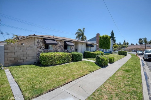 view of front of property with stucco siding, stone siding, fence, and a front lawn
