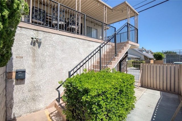 view of home's exterior with a gate, fence, and stairway