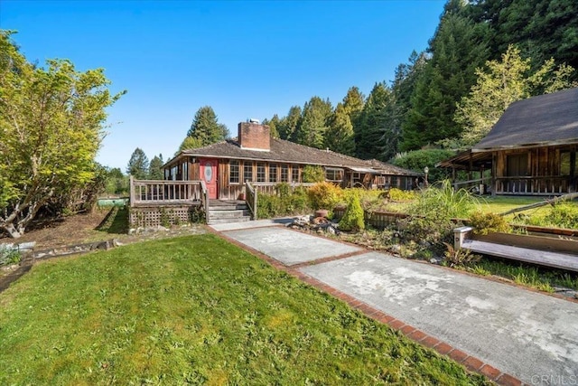ranch-style house with a front yard, a wooden deck, and a chimney
