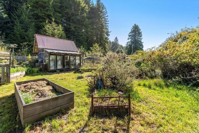 view of yard featuring an exterior structure, fence, an outbuilding, and a vegetable garden