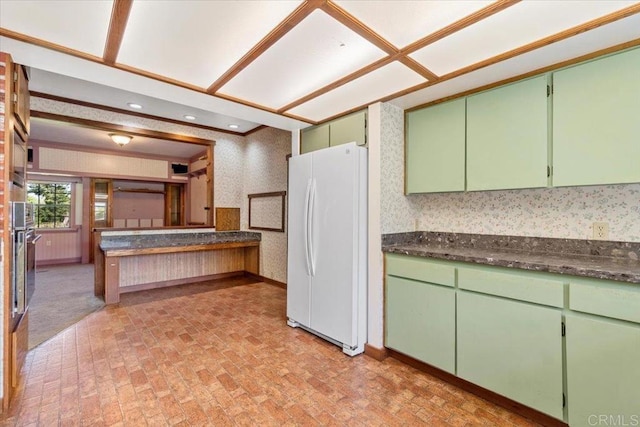 kitchen featuring freestanding refrigerator, dark countertops, and brick patterned floor