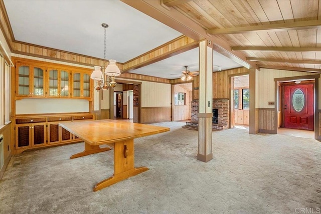 unfurnished dining area with wood walls, a brick fireplace, and carpet floors