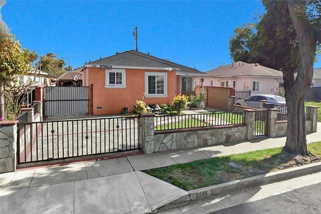 view of front of home featuring a fenced front yard, stucco siding, and a gate