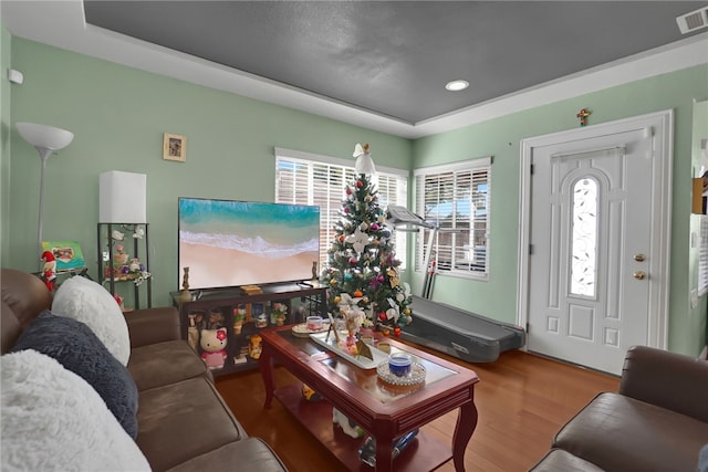 living room with recessed lighting, visible vents, a tray ceiling, and wood finished floors