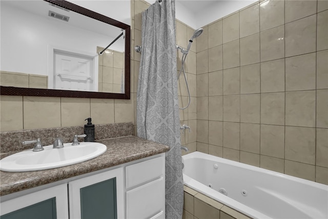 bathroom with a combined bath / shower with jetted tub, vanity, visible vents, and tasteful backsplash
