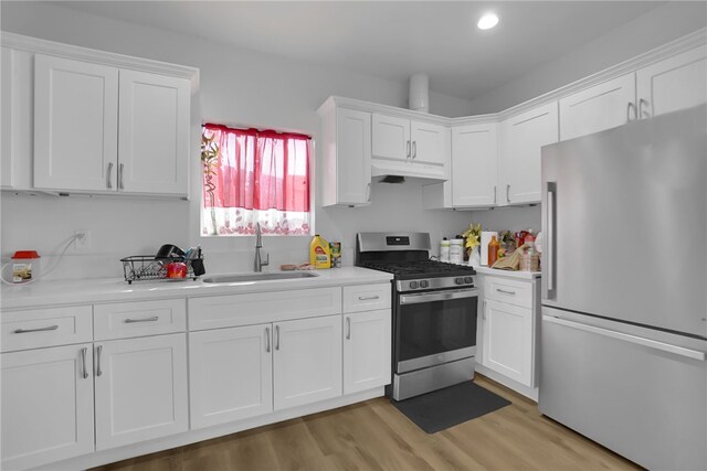 kitchen with stainless steel appliances, white cabinets, light countertops, and a sink