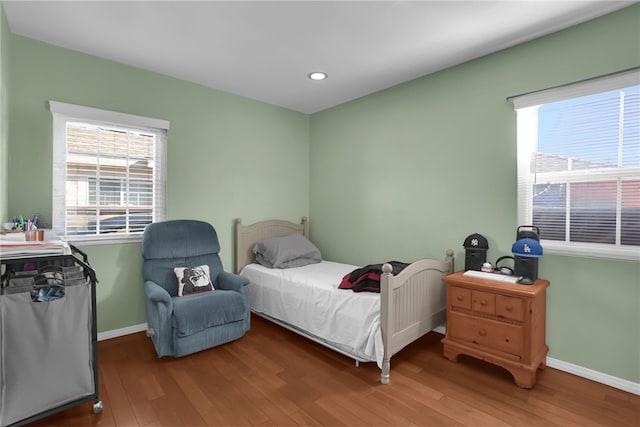 bedroom with multiple windows, baseboards, and wood finished floors