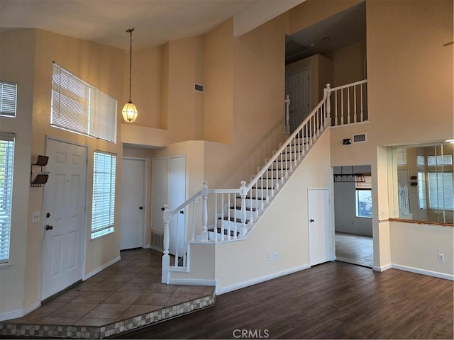 foyer entrance with baseboards, stairway, high vaulted ceiling, and wood finished floors